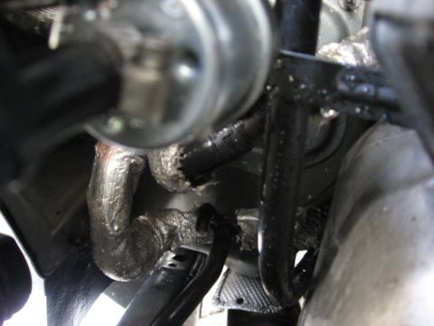 1994 Ford Bronco - A close-up view of the exhaust system of a 1994 Ford Bronco, showing insulated pipes and various metal components.