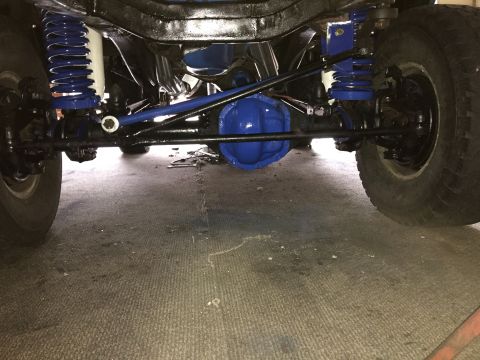 1974 Ford Bronco - The underside of a vehicle, likely a 1974 Ford Bronco, is shown with a focus on the suspension and drivetrain components. Blue-painted diff…