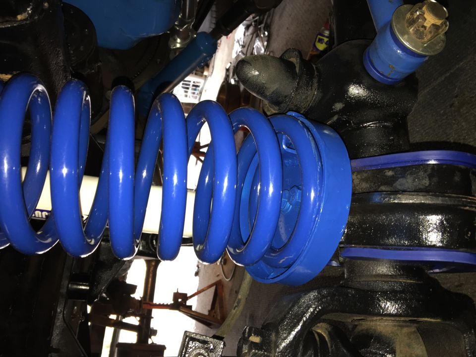 Blue coil spring and suspension parts on a vehicle.