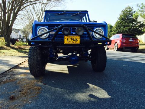 1974 Ford Bronco - A low-angle front view of a bright blue Ford Bronco with a black bull bar and yellow Virginia license plate reading "AL7946 ANTIQUE". A red…