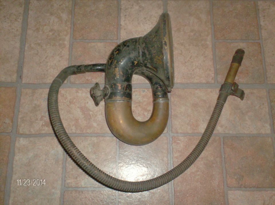 Vintage phonograph horn and flexible tube on a tiled floor