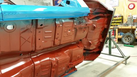 1970 Pontiac Trans Am - The underside of a vehicle is being worked on, with sections painted red and blue while mounted on a rotisserie.