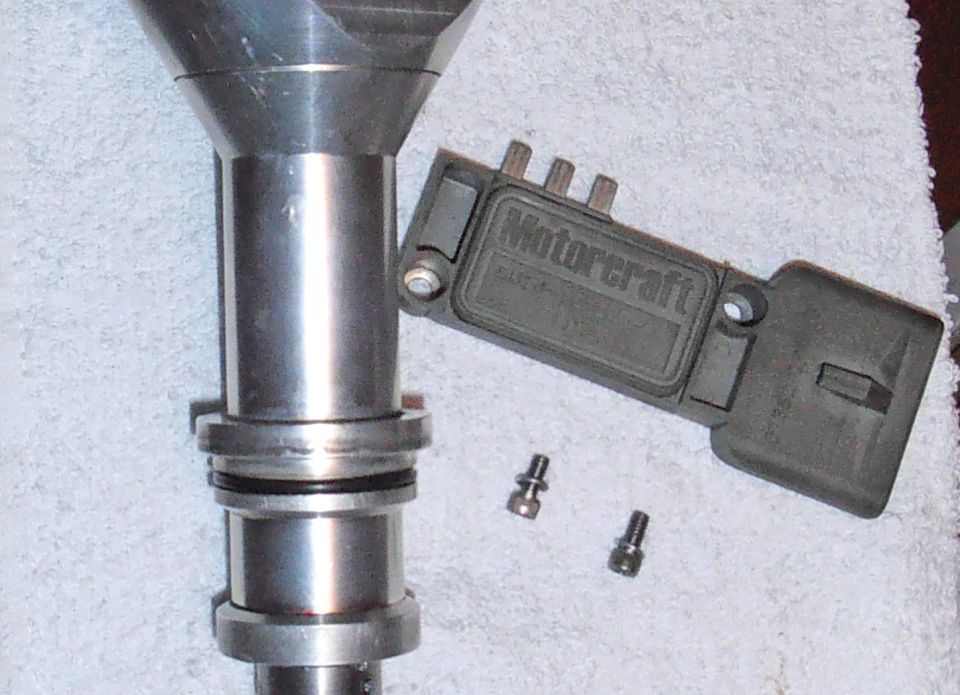 Motorcraft ignition module next to a distributor shaft and two screws