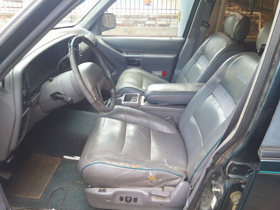 Interior view of worn gray leather seats and dashboard of a vehicle