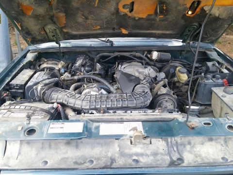 2000 Mercury Grand Marquis - The engine bay of a vehicle is shown with the hood open, revealing various mechanical parts.