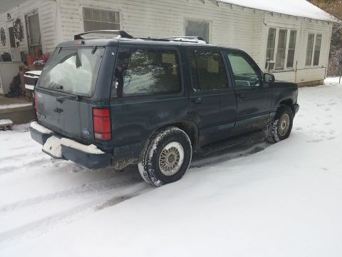 2000 Mercury Grand Marquis - A dark green Ford Explorer is parked in a snowy area next to a white house.