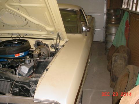 1971 Ford Ranchero - 1971 Ford Ranchero's engine bay and side profile, parked indoors with spare tires nearby.