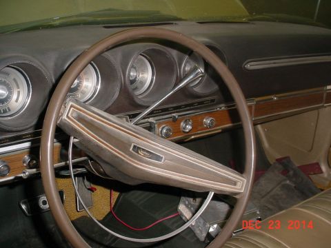 1971 Ford Ranchero - The interior of a vintage vehicle shows a brown steering wheel and dashboard with wood grain accents and circular gauges.