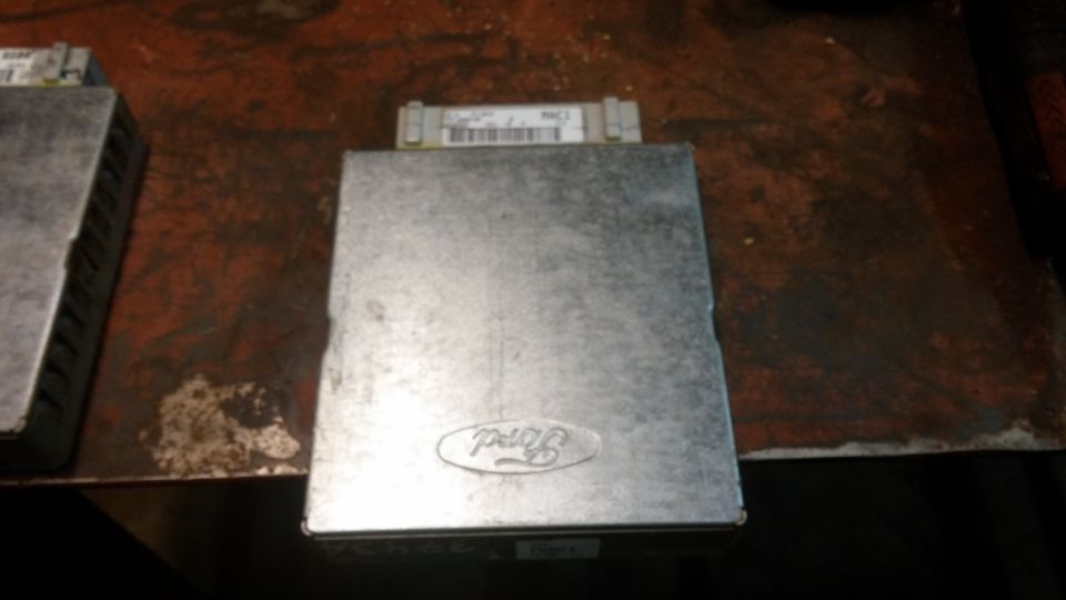 Silver Ford ECU with embossed Ford logo on a dark surface.
