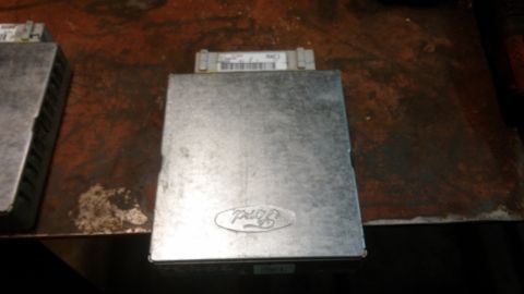 1995 Ford Bronco - A silver Ford ECU (Engine Control Unit) is shown on a dark, textured surface. The Ford logo is embossed on the top of the unit.