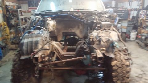 1995 Ford Bronco - The front end of a heavily modified, disassembled 1995 Ford Bronco is shown in a garage setting. The vehicle is missing its hood, fenders,…