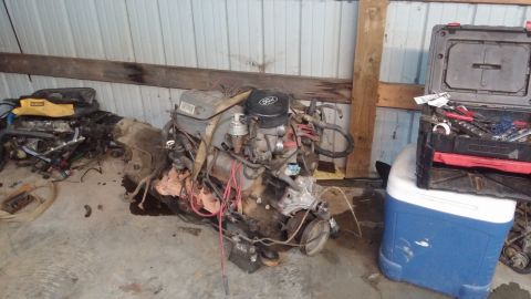 1995 Ford Bronco - A Ford engine and transmission assembly is shown on a concrete floor in a garage or workshop. A toolbox sits on top of a blue and white coo…