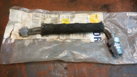 1995 Ford Bronco - A braided hydraulic hose with metal fittings is shown, partially covered by a clear plastic bag and FedEx shipping labels. The hose has a b…