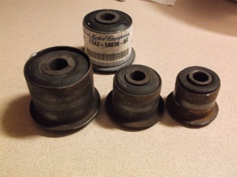 1999 Mercury Grand Marquis - Four rubber bushings are arranged on a speckled surface. One bushing is still in its original packaging, labeled "Ford Motor Company F8AZ-5…