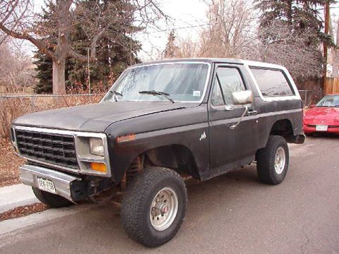 1981 Ford Bronco - This lifted Ford Bronco is parked on a street with a red car visible in the background.