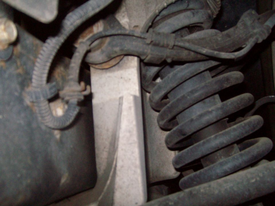 Close-up of vehicle suspension with coil spring and wire harness.