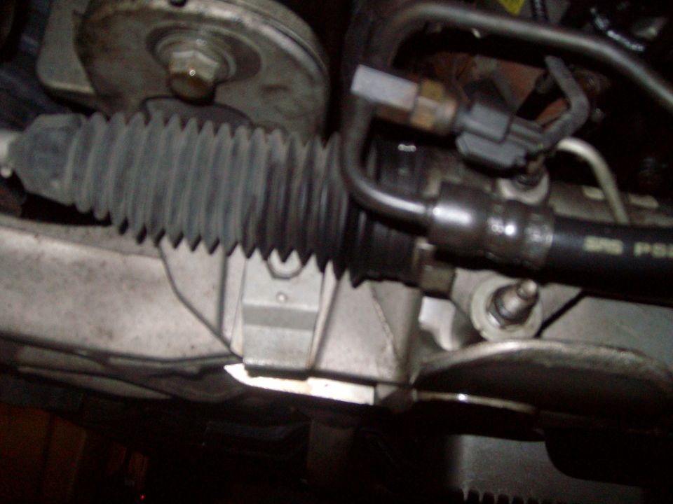 Close-up of a vehicle's power steering rack and pinion assembly.