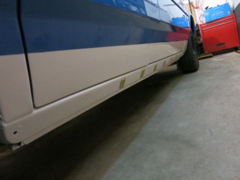 1991 Ford LTD Crown Victoria - Photograph of the side rocker panel and rear wheel of a two-tone car in a shop, not a technical document.
