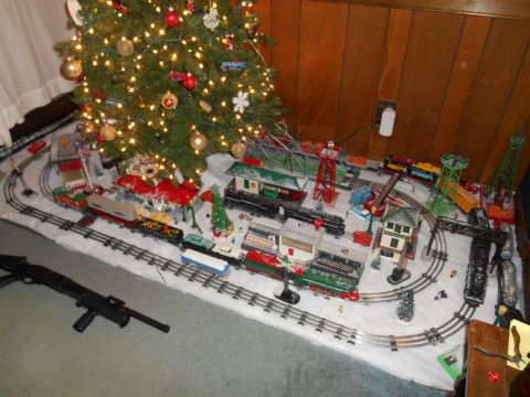 Christmas tree and model train set with snow and buildings.