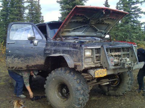 1990 Ford F-250 - A GMC truck is being worked on underneath with its hood open, a winch and off-road tires.
