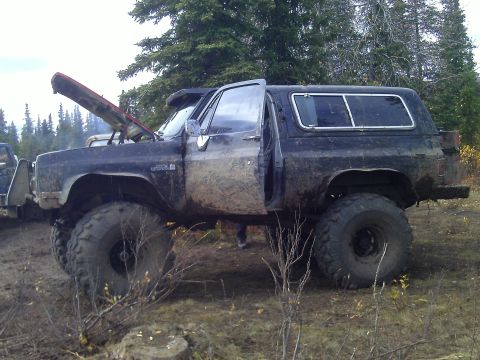1990 Ford F-250 - Modified SUV with large tires and hood open, seen in a natural, off-road setting.