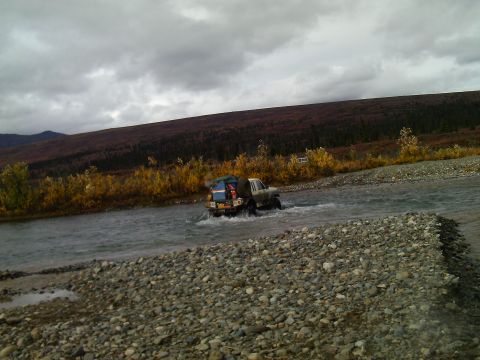 1990 Ford F-250 - Truck fords a river in a scenic, autumnal landscape.