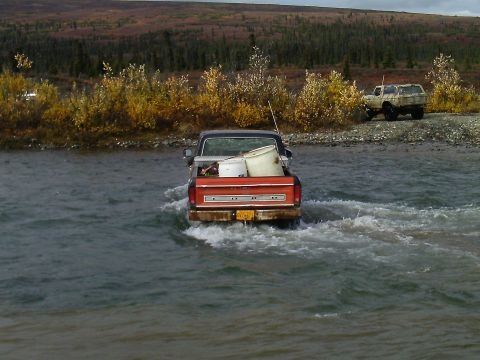 1990 Ford F-250 - A Ford F-Series truck navigates a shallow river with another vehicle visible on the bank.