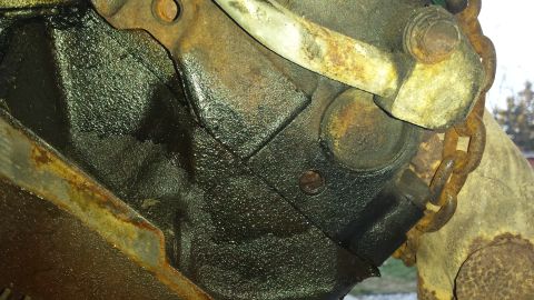 1995 Ford Bronco - Close-up of an engine block with visible oil residue and a rusty chain.