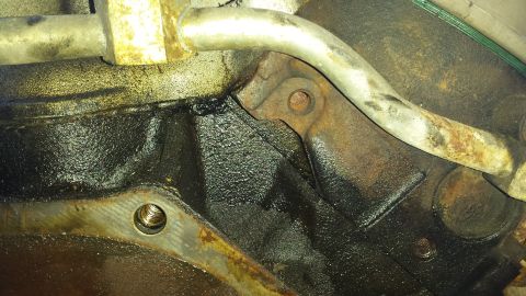 1995 Ford Bronco - Close-up view of an engine block showing oil leaks and metal piping.