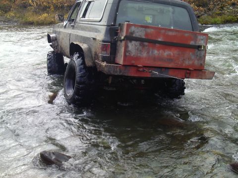 1990 Ford F-250 - Off-road SUV with custom bed navigates through a shallow river.