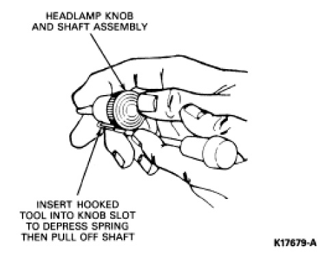 1990 Ford Bronco - Service procedure illustration showing a hooked tool inserted into the headlamp knob slot to depress the spring and remove the shaft.