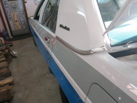 1991 Ford LTD Crown Victoria - Side view of a two-tone car with a white vinyl top and chrome accents, parked indoors.