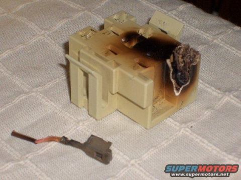1990 Ford Bronco - A burnt electrical connector and its detached wire lie on a textured surface.