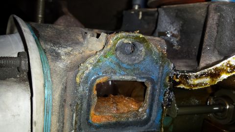 1995 Ford Bronco - Close-up of a heavily corroded engine component showing signs of wear and oil leakage.