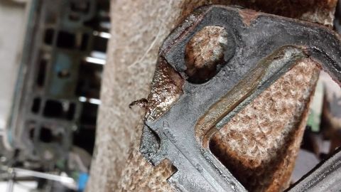1995 Ford Bronco - A close-up view of a used exhaust manifold gasket, showing signs of wear and oil residue.