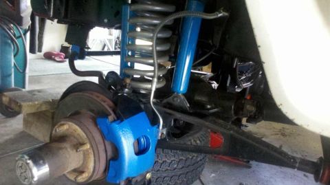 1982 Ford Bronco - Close-up of a vehicle's front suspension system, showing newly painted blue brake components and suspension parts.