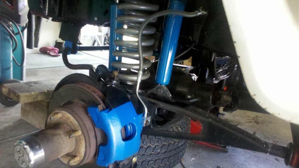 Front suspension with blue brake caliper and shock absorber, rusty brake rotor, and tire