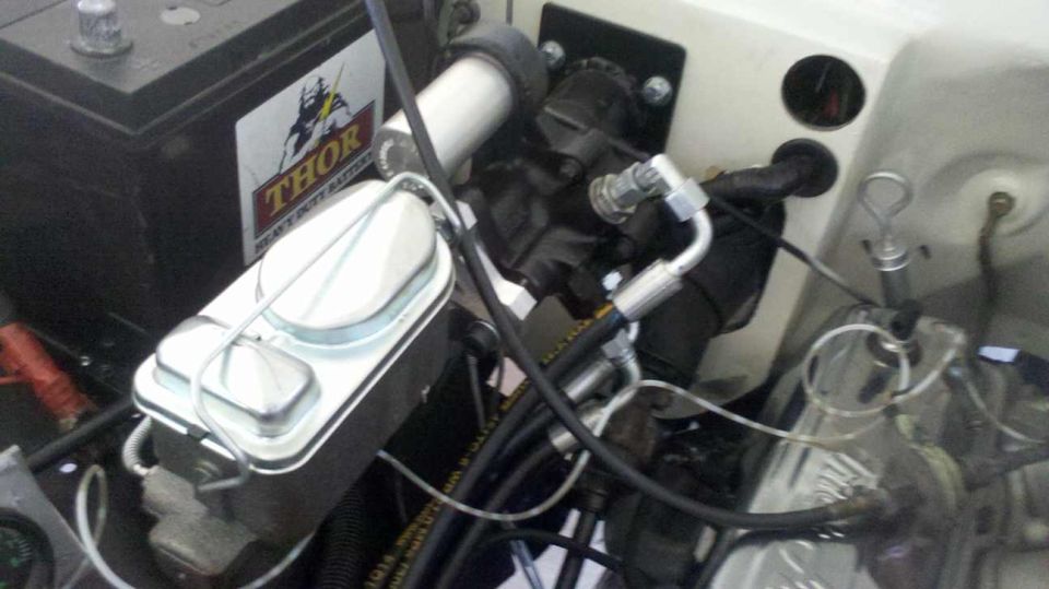 Engine bay with brake master cylinder, battery, and hoses. Supermotors.net logo visible