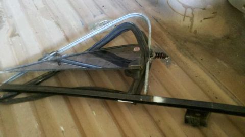 1982 Ford Bronco - A car door window assembly is shown lying on a wooden surface.
