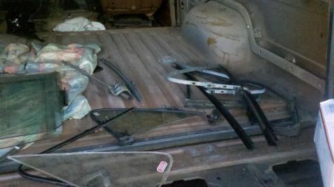 1982 Ford Bronco - Various window components and other items are stored in the cargo area of a vehicle.