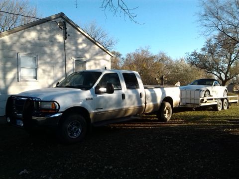 2000 Ford F-250 - A white 2000 Ford F-250 is seen from the side, towing a car on a trailer.