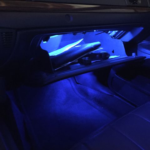 2007 Ford Crown Victoria - The interior of a car's glove box is illuminated with blue LED lights, showing some papers and a dark object inside.