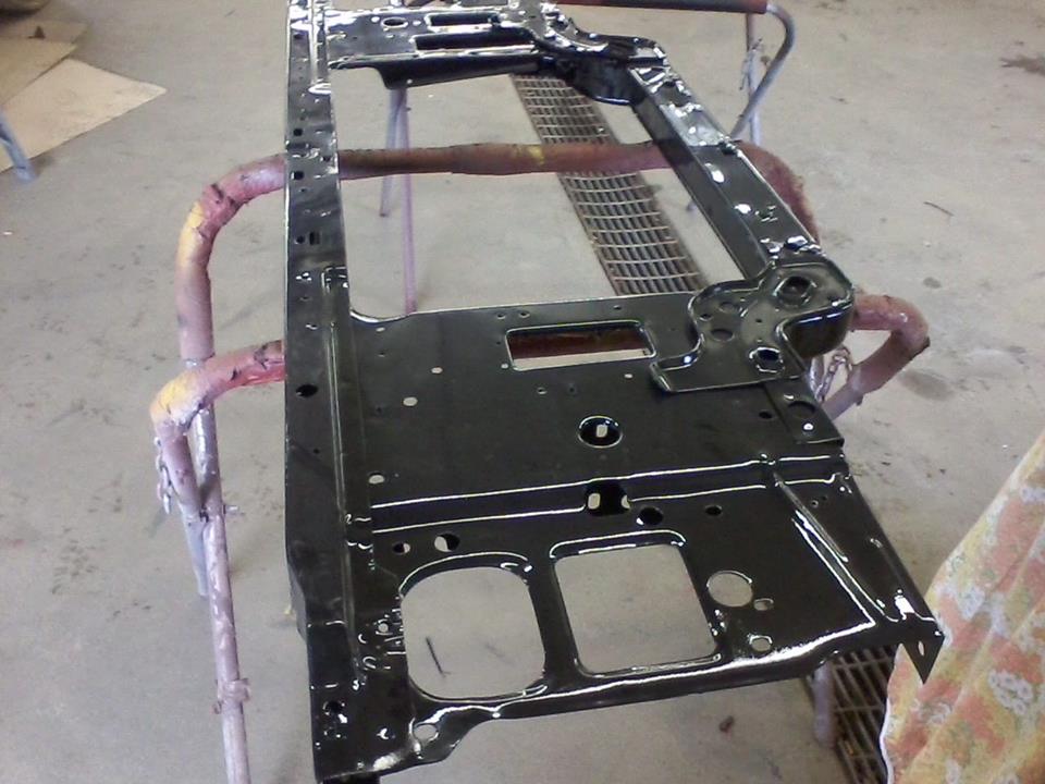 Freshly painted glossy black metal body panel on a red work stand in a garage