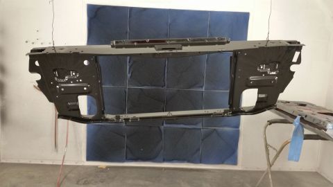 1970 Pontiac Trans Am - A car's front subframe is suspended for painting in a booth, with blue sound-dampening panels in the background.