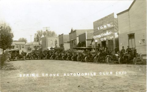 1909 Ford Model T - A row of early automobiles are parked in front of a Ford dealership, identified as 'Onsgaard & Os'.