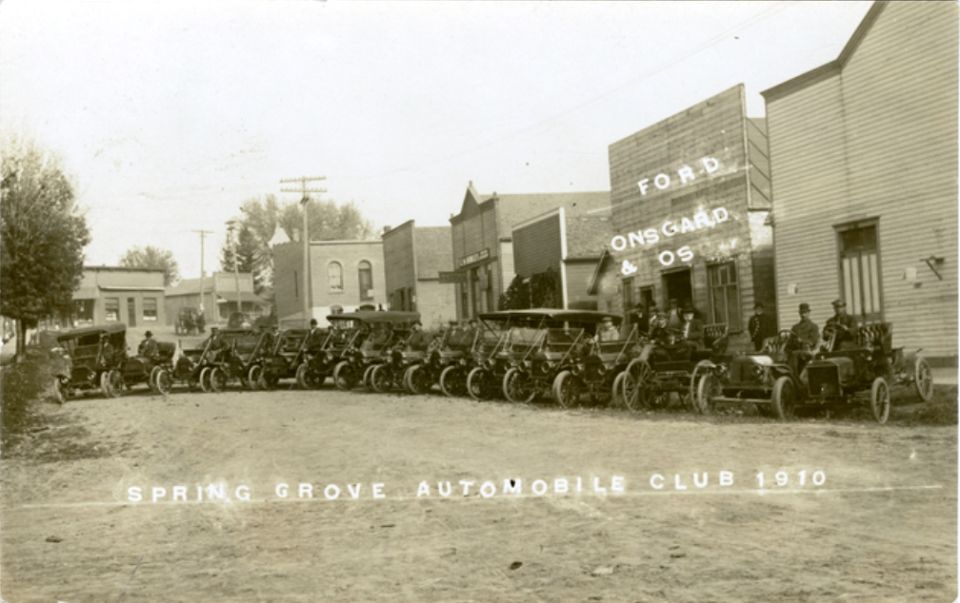 Spring Grove Automobile Club lined up with cars in front of a Ford dealership