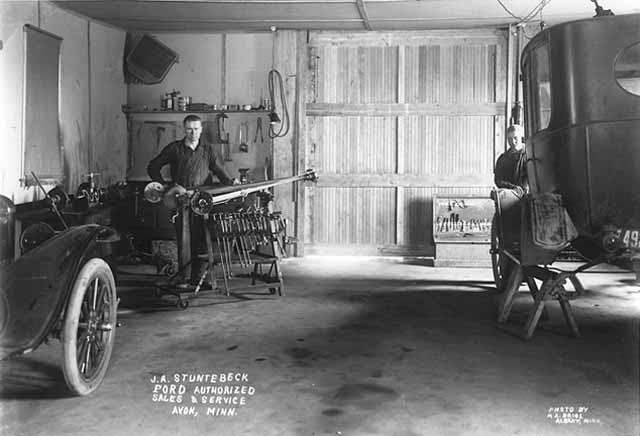 1909 Ford Model T car and a horse-drawn carriage in a garage