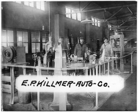 1909 Ford Model T - Workers operate machinery inside the E.P. Hillmer Auto Co. repair shop, with a car visible in the background.