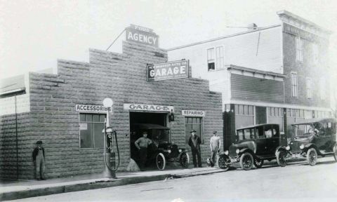 1909 Ford Model T - A 1909 Ford Model T is visible outside a Ford Agency garage, with two other vehicles parked along the street.