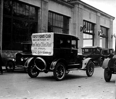 1909 Ford Model T - A 1909 Ford Model T, identified as the first car manufactured at the Twin Cities Plant, is seen here with other vehicles.